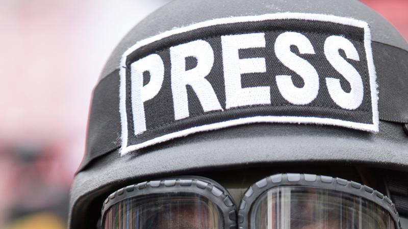 a member of the press in a military helmet