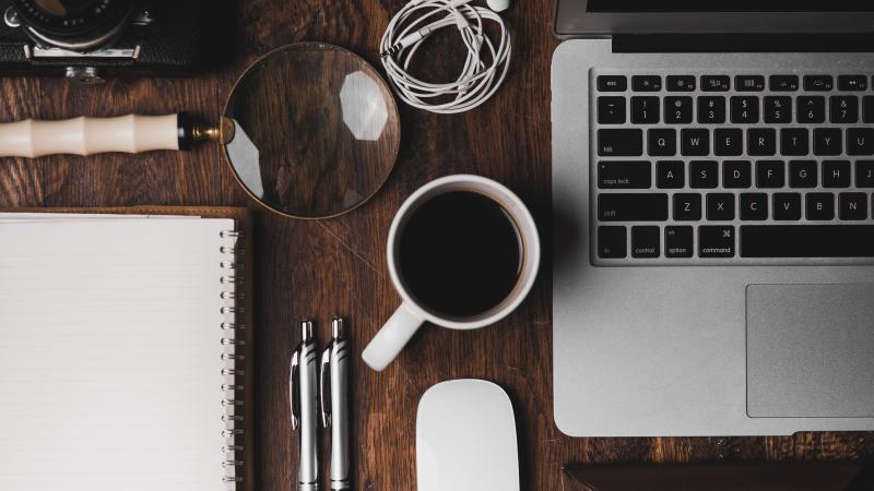 a workspace with notebook, coffee, laptop and notebook